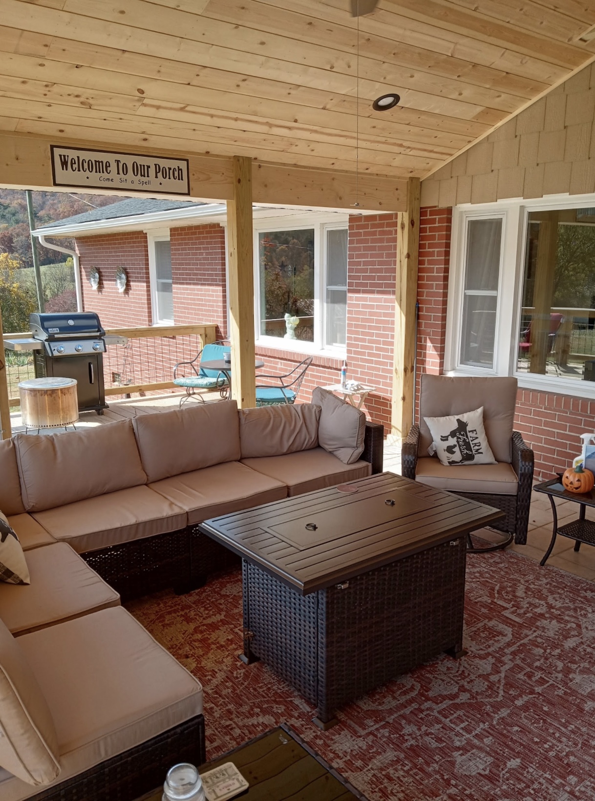 Outdoor living room under covered porch with T&G ceiling and fire table — WNC