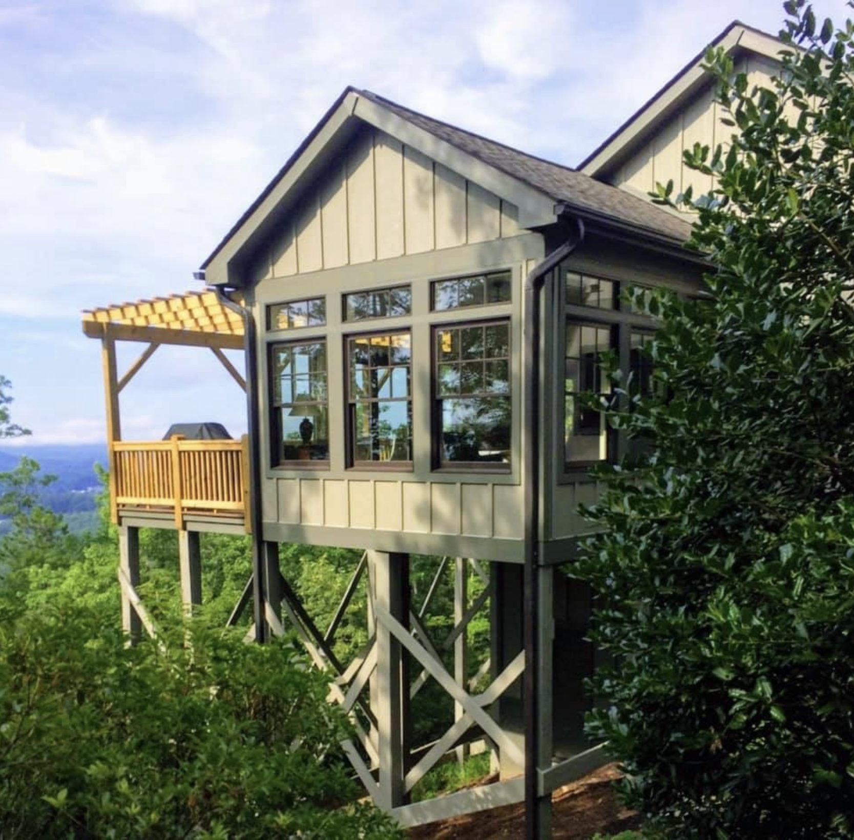 Board-and-batten sunroom addition on stilts with mountain view — WNC